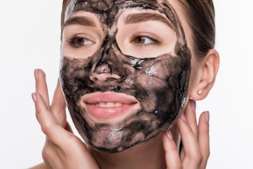 Young woman with a charcoal mask on her face, showcasing a skincare routine