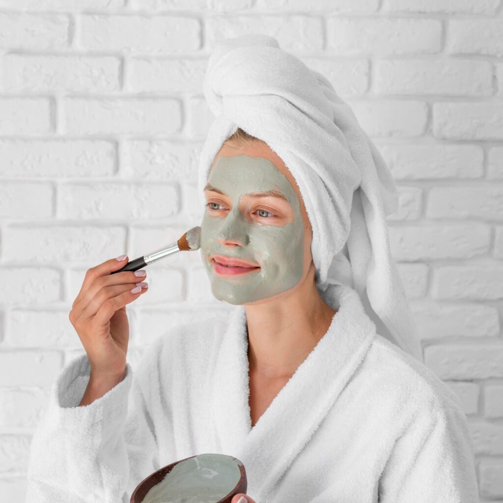 A woman applying a face mask as final step of her face clean up routine for refreshed and glowing skin.