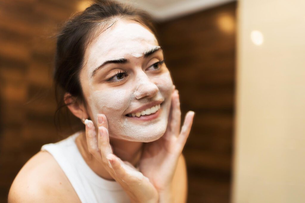 A girl doing a face clean up by exfoliating her skin with a gentle facial scrub.