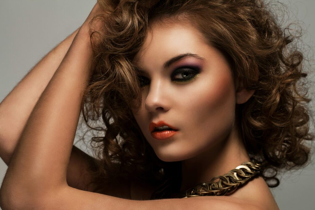 Beautiful woman with curly hair and makeup perfectly suited for dusky skin, highlighting makeup techniques for enhancing dusky skin tones.