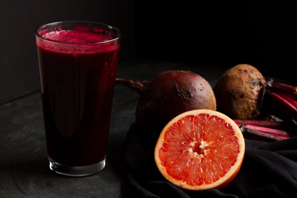 Beetroot juice in a glass with orange slices, showcasing the natural health benefits of beetroot powder for skin rejuvenation.